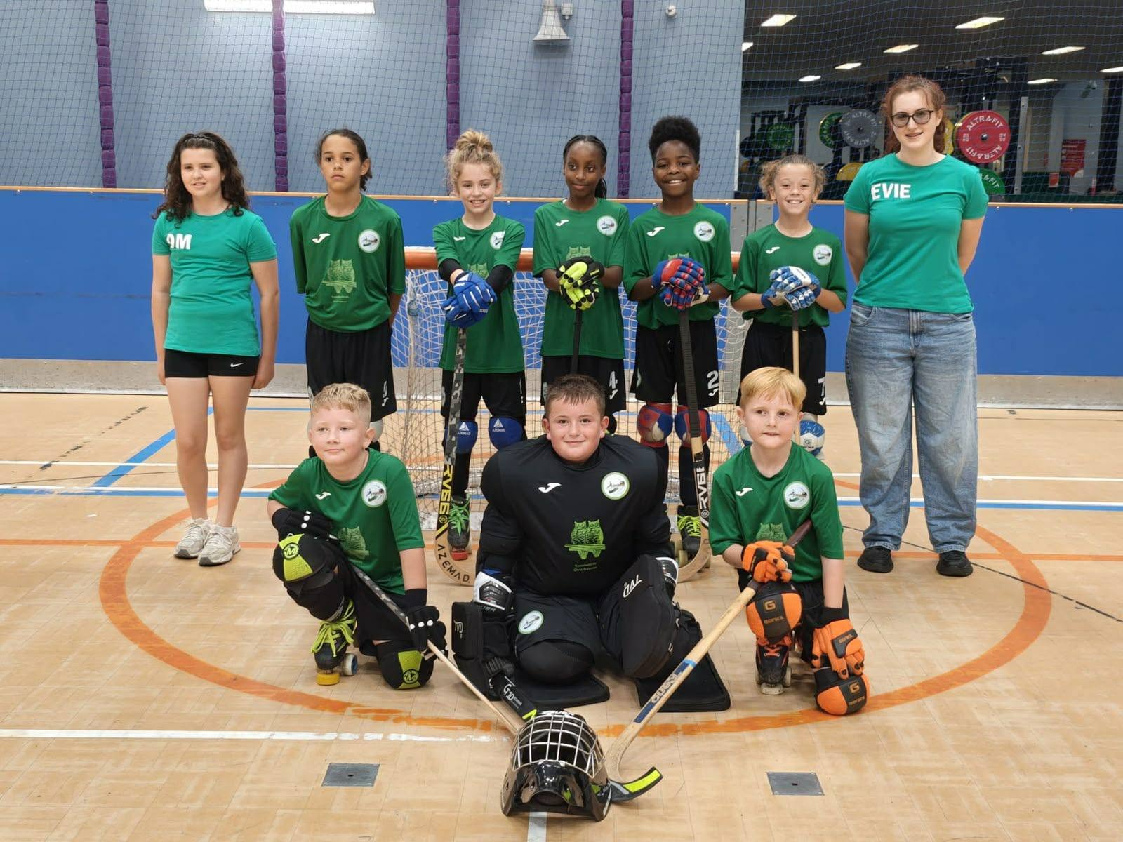 A young junior team with sticks and skates in front of their goal